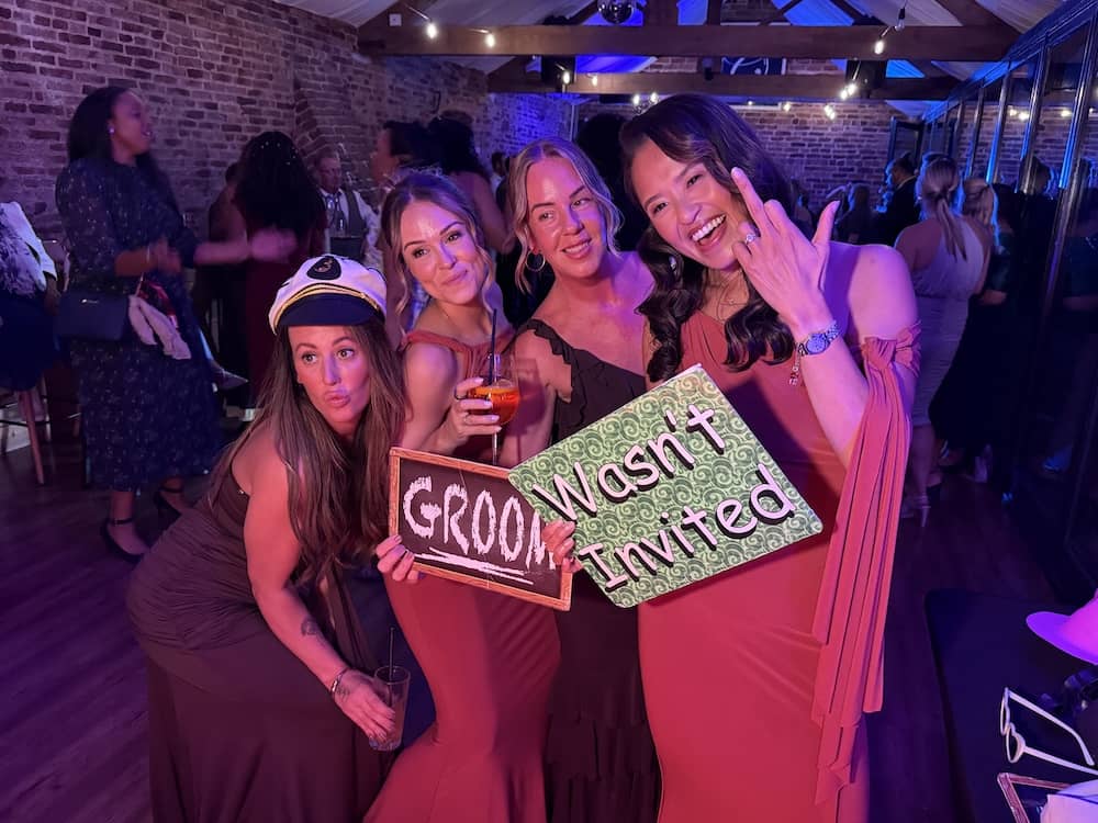 Wedding guests posing with Groom Wasn't Invited sign at the Magic Mirror