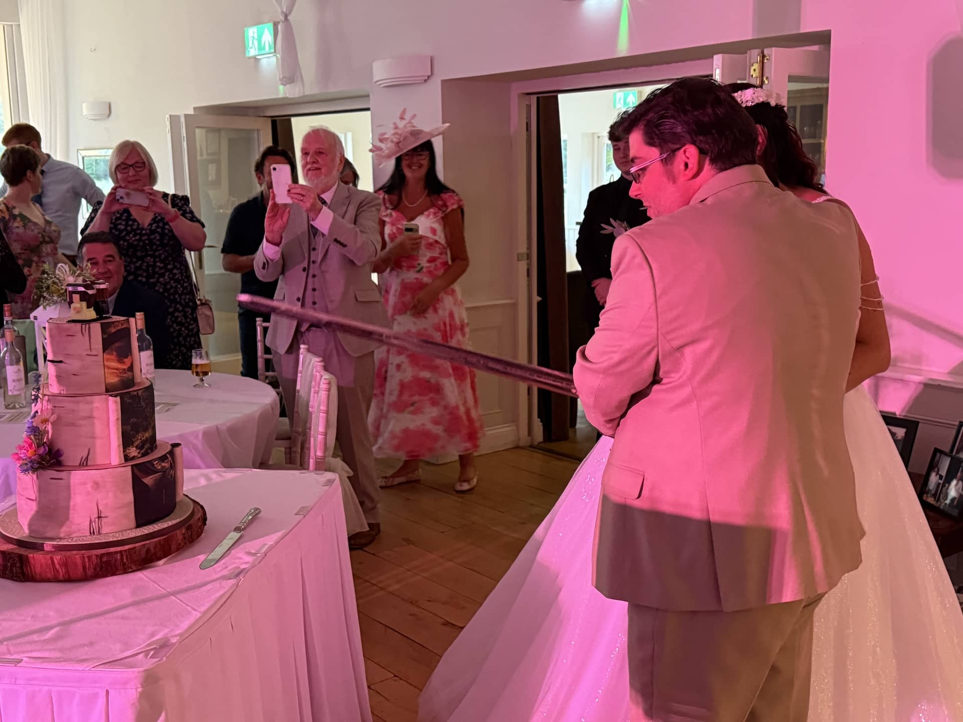 Bride and groom cutting their wedding cake with a Lord of the Rings sword