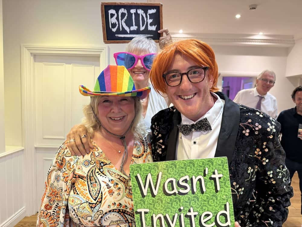 Wedding guests posing with the Wasn't Invited Magic Mirror prop