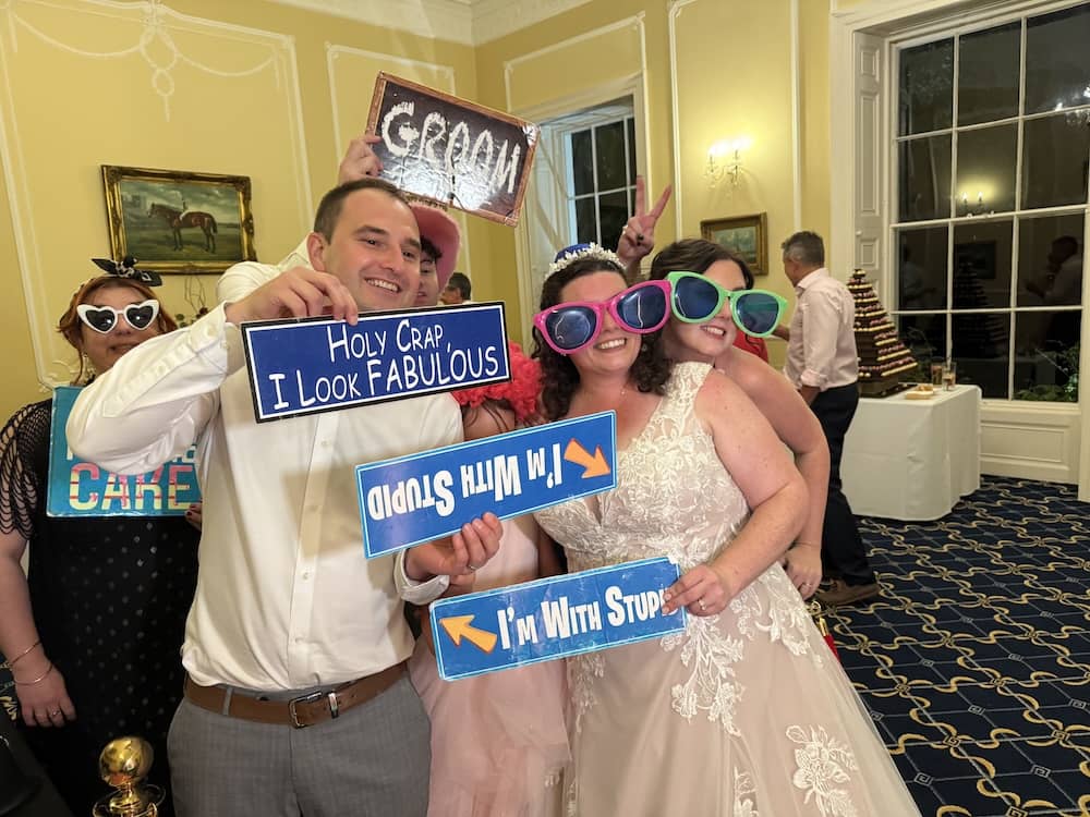 Bride and wedding guests posing with Magic Mirror props