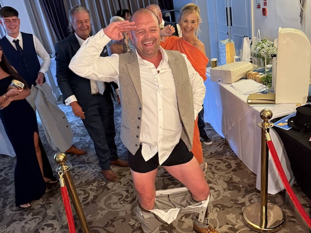 Wedding guest saluting while joking around with his trousers down at the Magic Mirror