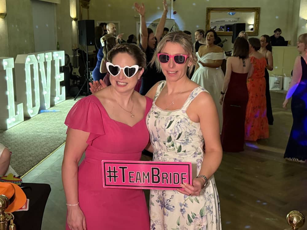 Wedding guests posing with props at the Magic Mirror at Rogerthorpe Manor